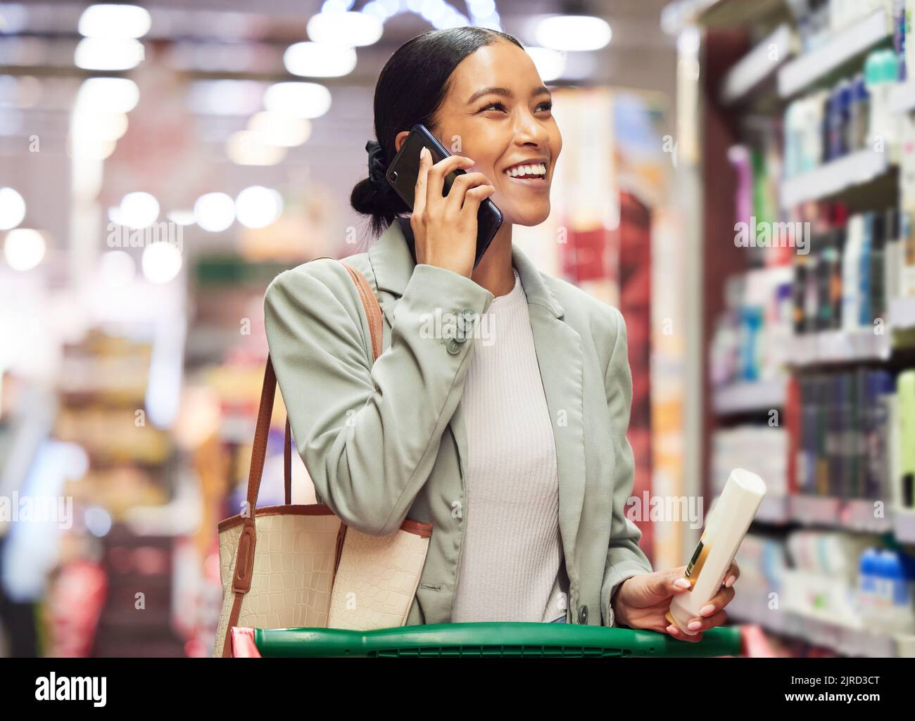 Supermercato cliente negozio parlare al telefono shopping e alla ricerca di vendita al dettaglio locale per sano, benessere e igiene personale shampoo. Sorridere e felice Foto Stock