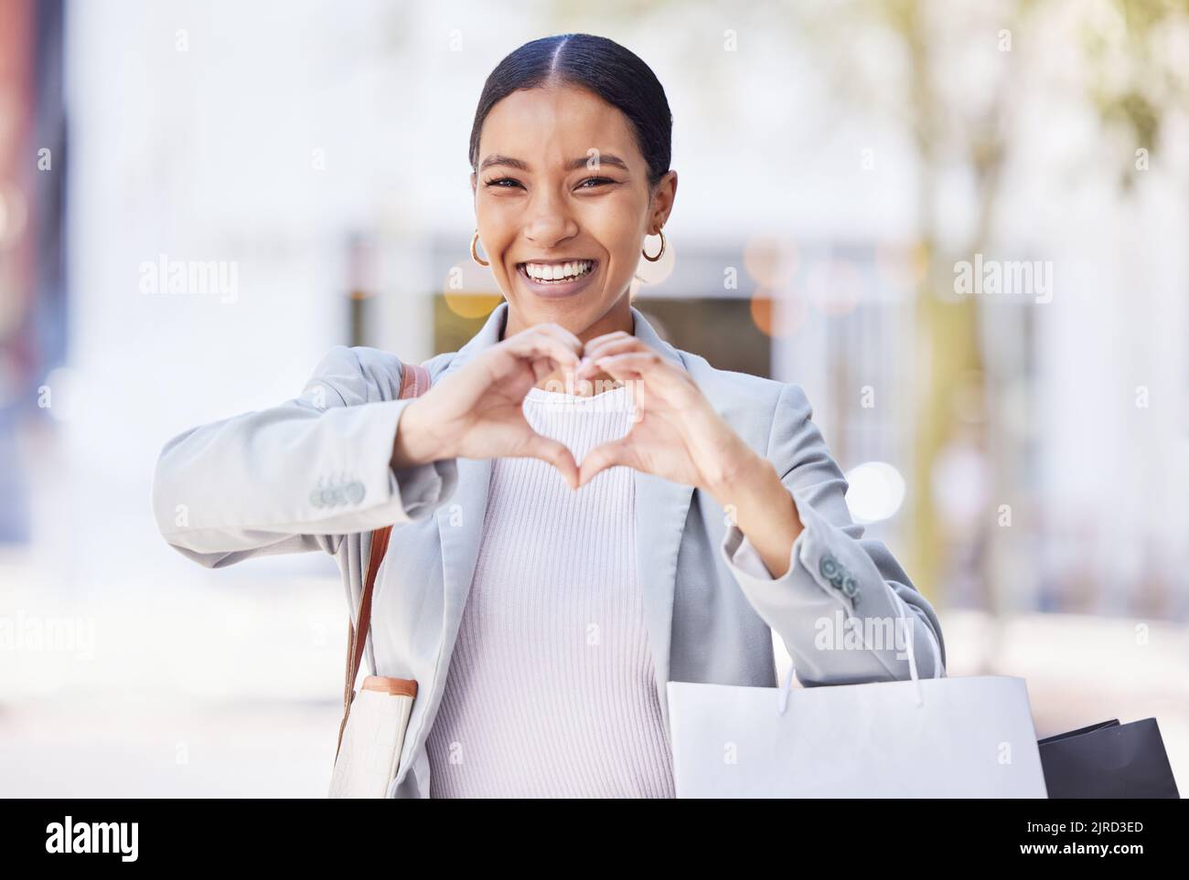 Donna dello shopping con segno di amore e cuore o mano in una strada urbana con borse al dettaglio. Professionale di moda donna, cliente e designer Foto Stock