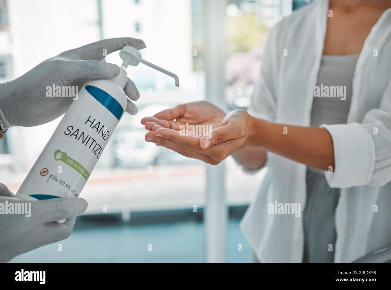 Igienizzatore o sanitizzante donna che pulisce le mani per evitare la diffusione di cocid in aeroporto. Primo piano di una femmina con disinfettante antibatterico Foto Stock