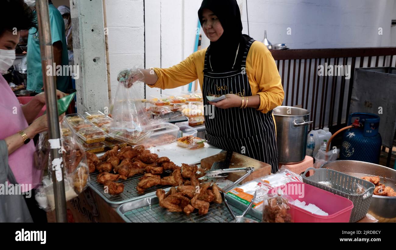 Denaro cambiare mani marciapiede Street Food Vendor su Peuberri Road a Bangkok Thailandia Foto Stock