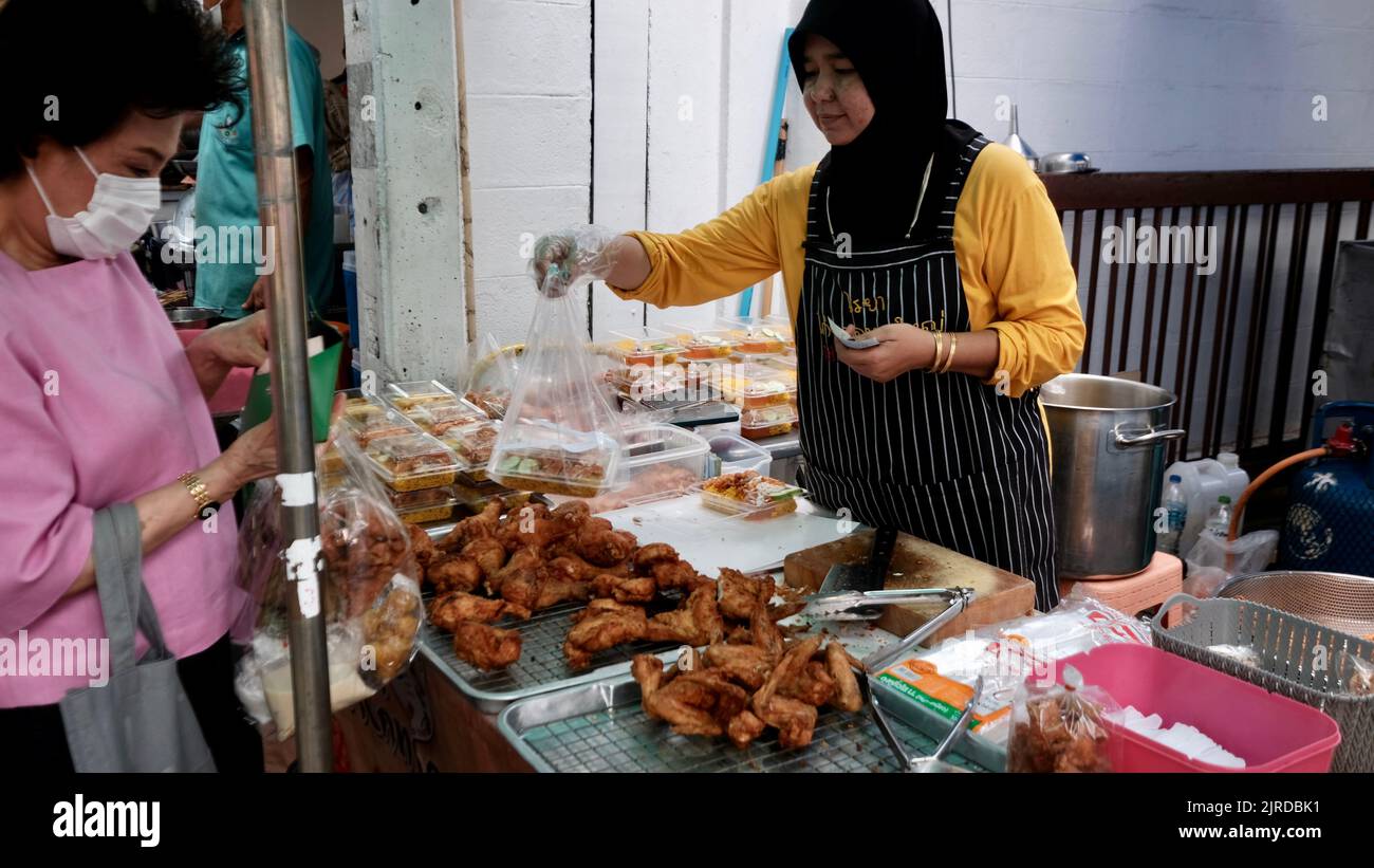 Denaro cambiare mani marciapiede Street Food Vendor su Peuberri Road a Bangkok Thailandia Foto Stock