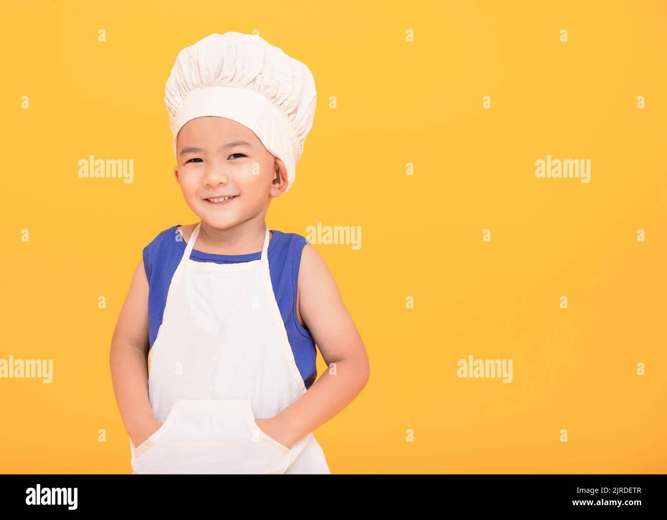 Ragazzo felice in uniforme chef su sfondo giallo Foto Stock