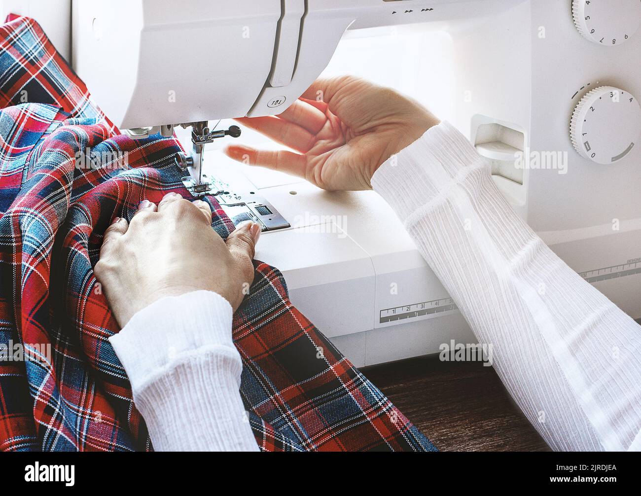Mani femminili nel processo di cucire un panno colorato sulla macchina da cucire. Concetto di stile di vita Foto Stock