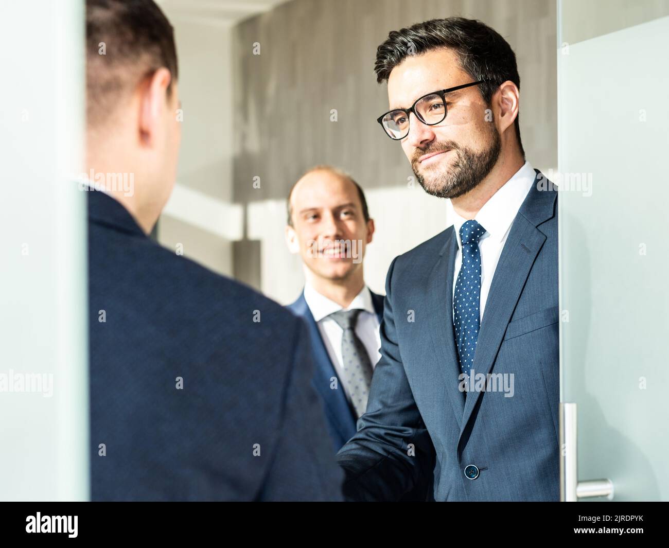 Gruppo di fiduciosi uomini d'affari salutano con una stretta di mano durante la riunione d'affari in ufficio moderno o chiudendo l'accordo di trattativa scuotendo le mani. Foto Stock