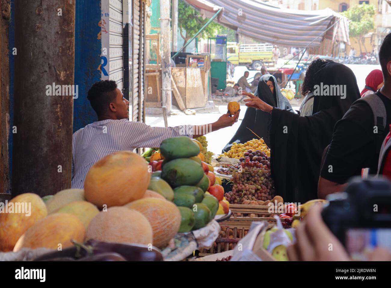 ESNA, LUXOR, EGITTO - 13 AGOSTO 2022: Donne velate che indossano abiti neri tradizionali che comprano frutta al mercato locale nella città di Esna, a sud di Luxor. Foto Stock