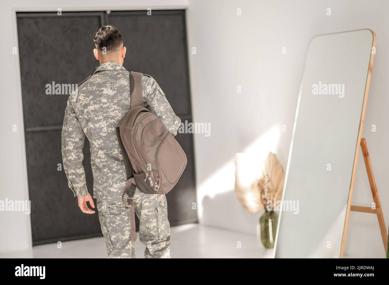 Soldato nella divisa mimetizzata che lascia la sua casa Foto Stock