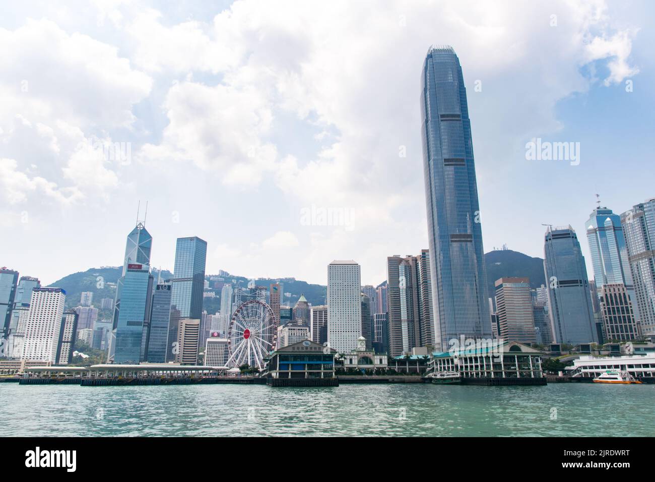 Lo skyline di Hong Kong, visto dallo Star Ferry, comprende grattacieli moderni, la ruota panoramica e il porto centrale. Foto Stock