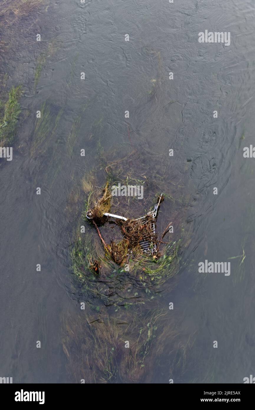 Una risorsa sprecata, un carrello della spesa è stato scartato nell'acqua, lasciato per inquinare lentamente i suoi dintorni. Foto Stock