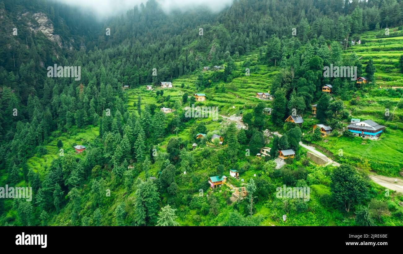 Paesaggio aereo di case locali nel villaggio di montagna di Jibhi circondato da verde e foresta di cedri Foto Stock