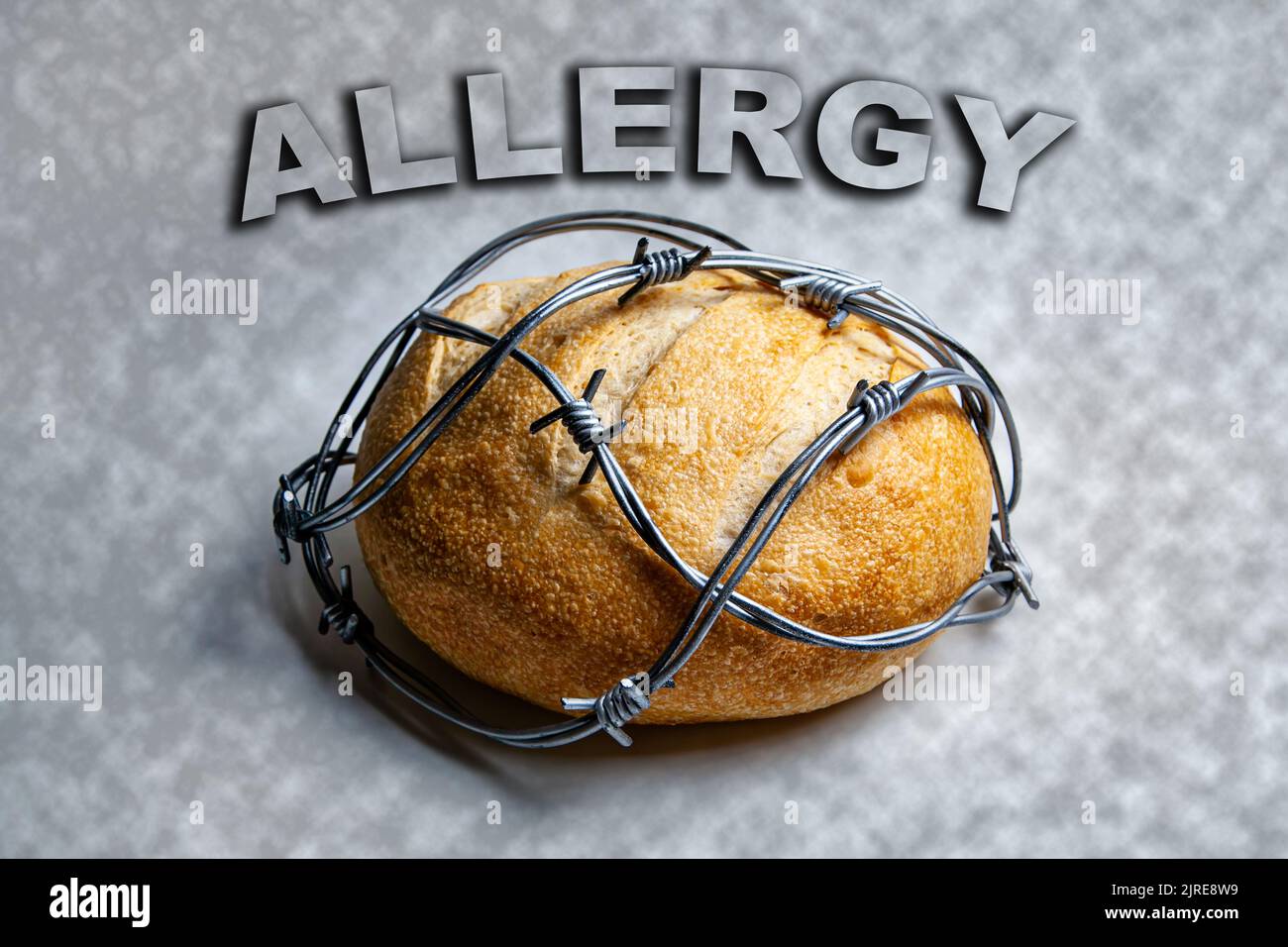 Allergia al pane, ai componenti del pane, al glutine. Pagnotta di pane rotondo di grano avvolto con filo spinato. Foto Stock