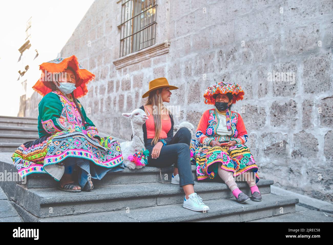 Femmina turista con le donne peruviane tradizionali un bambino lama in strada, Arequipa, Perù. Messa a fuoco selettiva Foto Stock