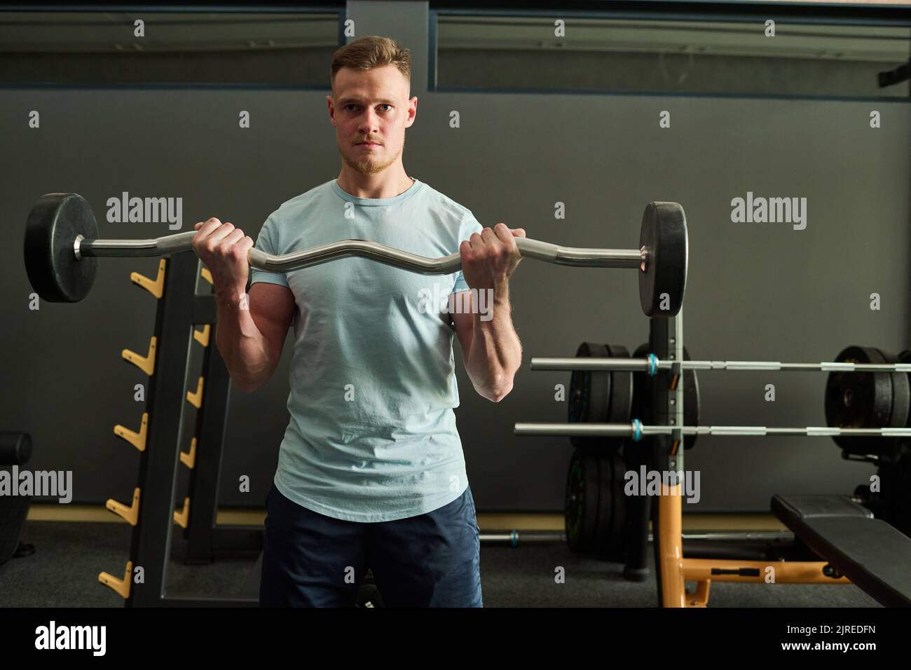 Ritratto di giovane in piedi in centro benessere e fare esercizi con il barbell Foto Stock