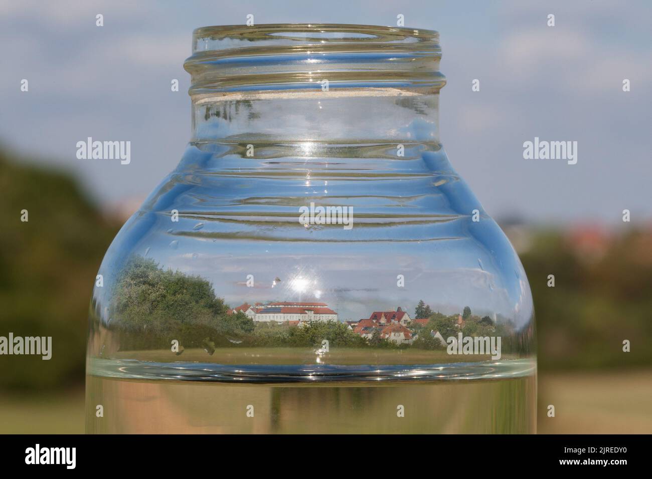 Asciugato, una città che si riflette in una bottiglia d'acqua. La crisi climatica sta inoltre drenando acqua in Germania. I livelli delle acque sotterranee stanno diminuendo e minacciano il Foto Stock