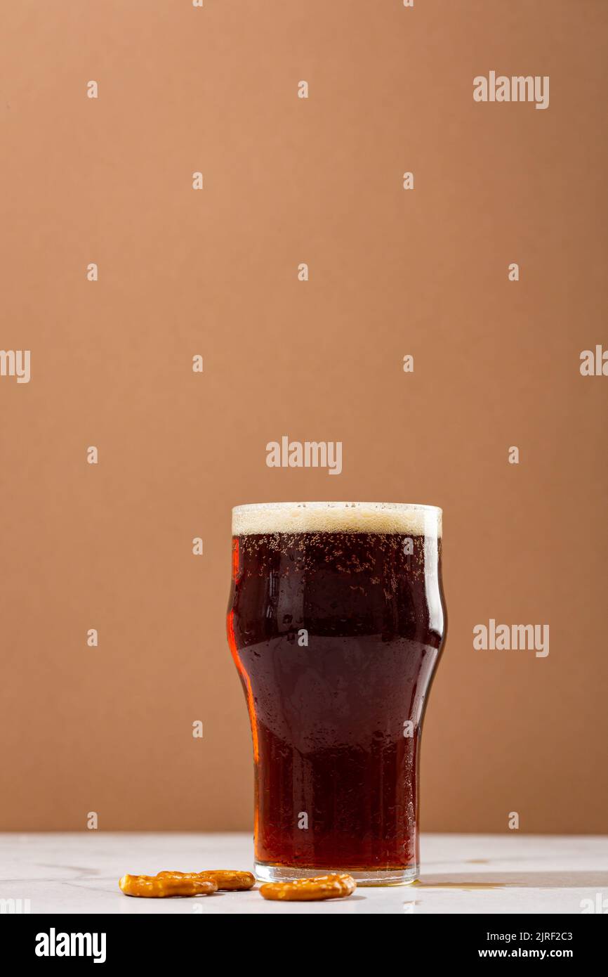 Primo piano di un bicchiere di birra marrone con schiuma sullo spazio per la copia di cibi e bevande Foto Stock