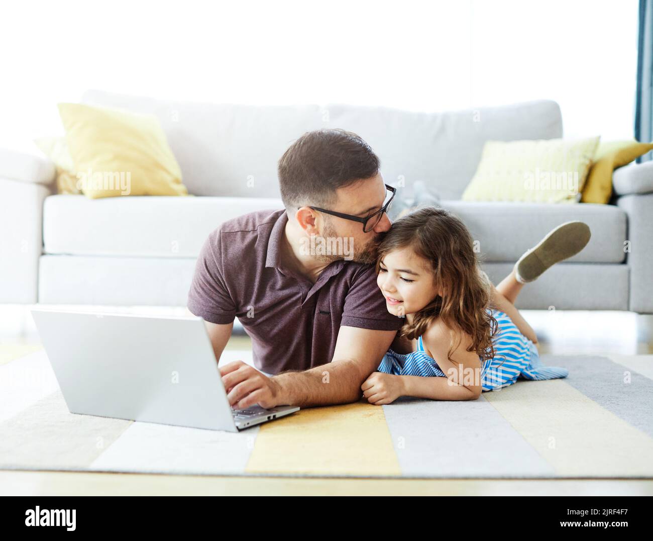 bambino padre figlia laptop famiglia gir computer genitore insieme tecnologia casa bacio sdraiato Foto Stock