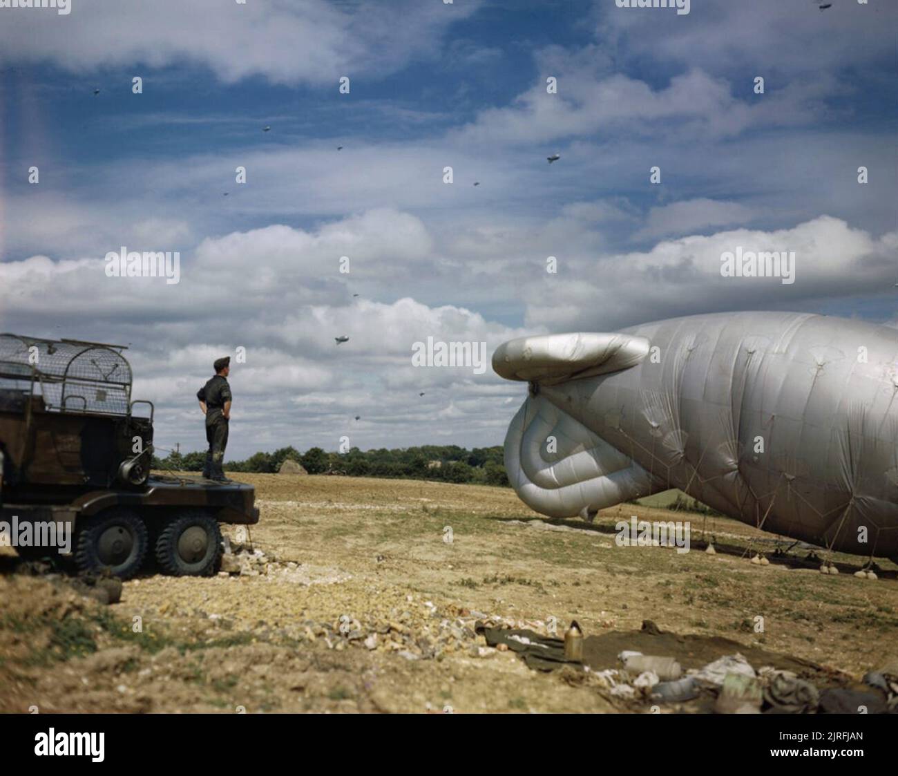 La parte anteriore di casa in Gran Bretagna 1939-1945 un palloncino di barrage del comando di palloncino attaccato ad un winching autocarro e ancorato al terreno in prossimità di Biggin Hill, Kent. Sullo sfondo di un certo numero di airborne palloncini sono visibili. Grandi numeri di barrage palloncini erano situati in tutto il sud-est si avvicina a Londra per combattere la crescente minaccia del V-1 battenti bombe lanciate da Pas de Calais a partire da giugno 1944. Foto Stock