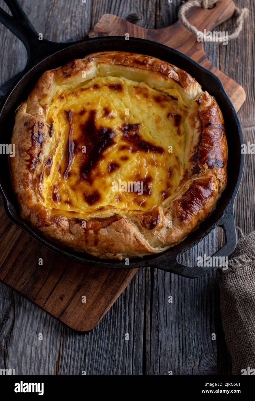 Crostata di pasta sfoglia con ripieno di cagliata di limone cagliata al forno in una padella di ghisa e servita isolata su tavola di legno. Vista dall'alto Foto Stock