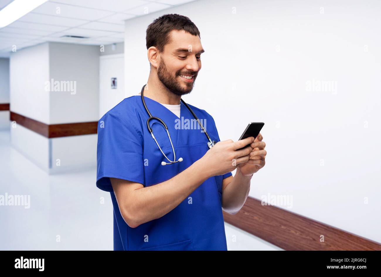 medico sorridente o infermiera maschile utilizzando lo smartphone Foto Stock