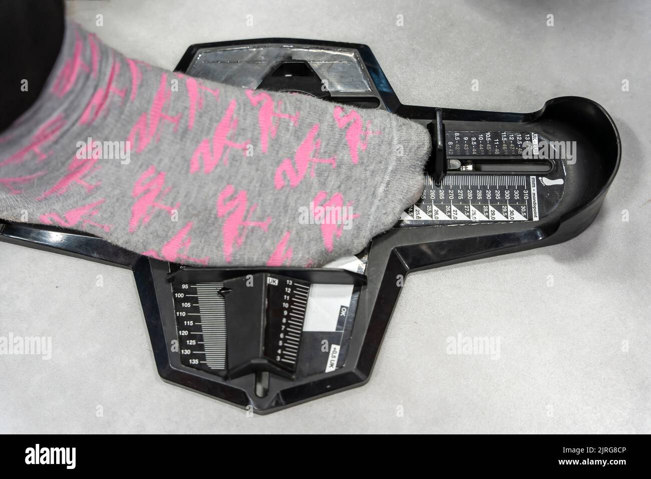 Ragazza misura scarpe in negozio. Dispositivo per determinare la lunghezza del piede Foto Stock