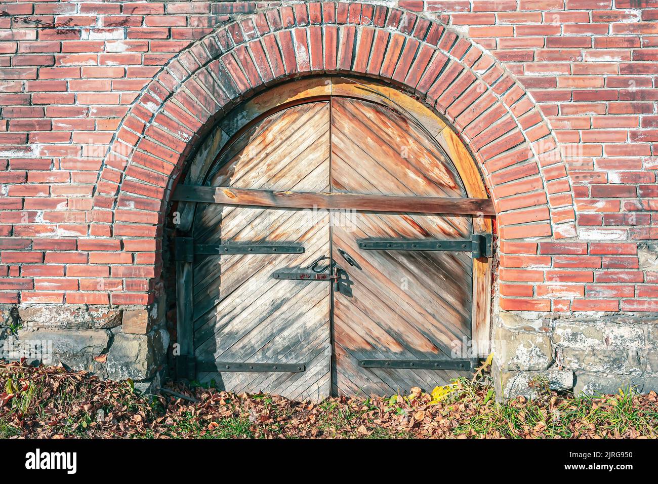Salite a bordo di porte di legno di un antico castello in mattoni, spazzato dal fogliame autunnale Foto Stock