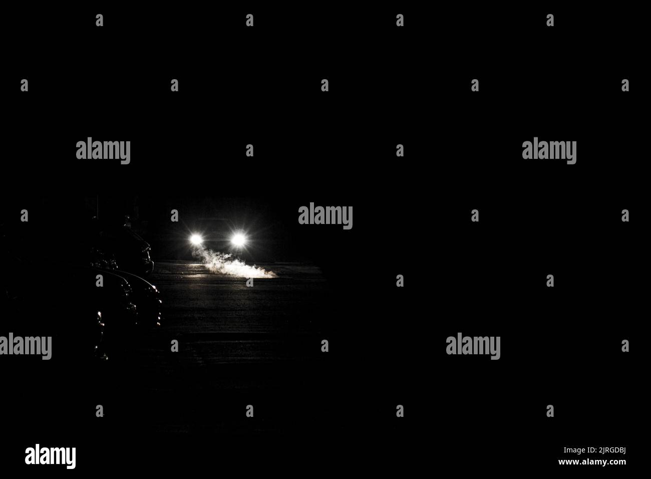 Paesaggio notturno sotto forma di vapore e auto illuminate da fari per auto. Foto Stock