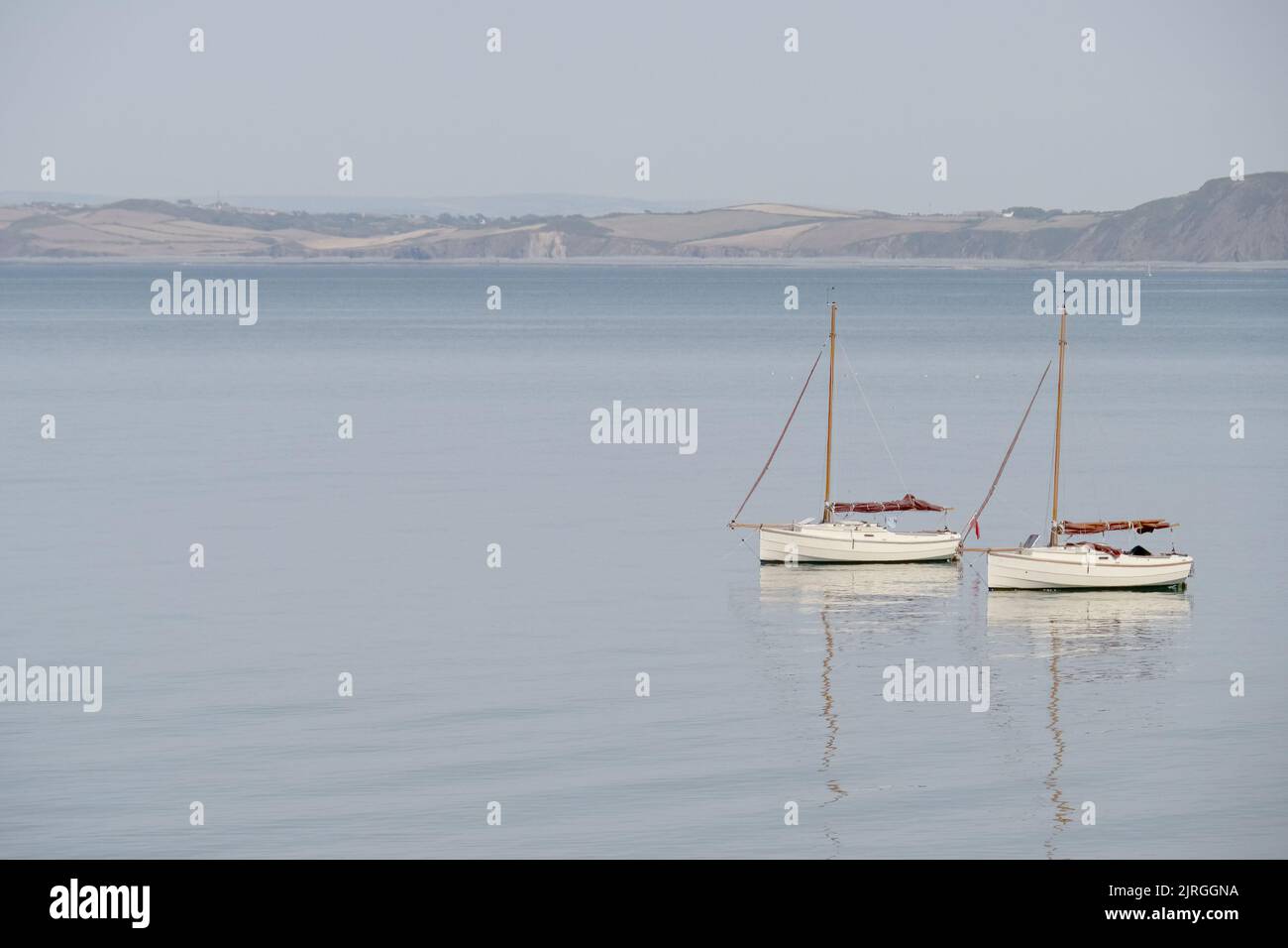 Due barche a vela molto simili su acque calme con riflessione. Sereno scenario tranquillo. Foto Stock