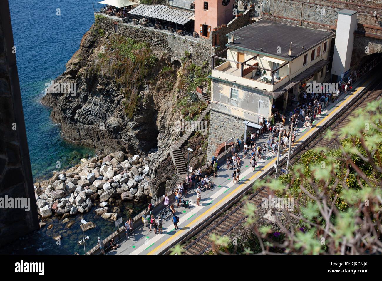 Folla in attesa in una stazione ferroviaria in una località balneare, in popolare città turistica delle cinque Terre, Liguria, italia sotto il sole caldo in alry afteroon, 2021 Foto Stock