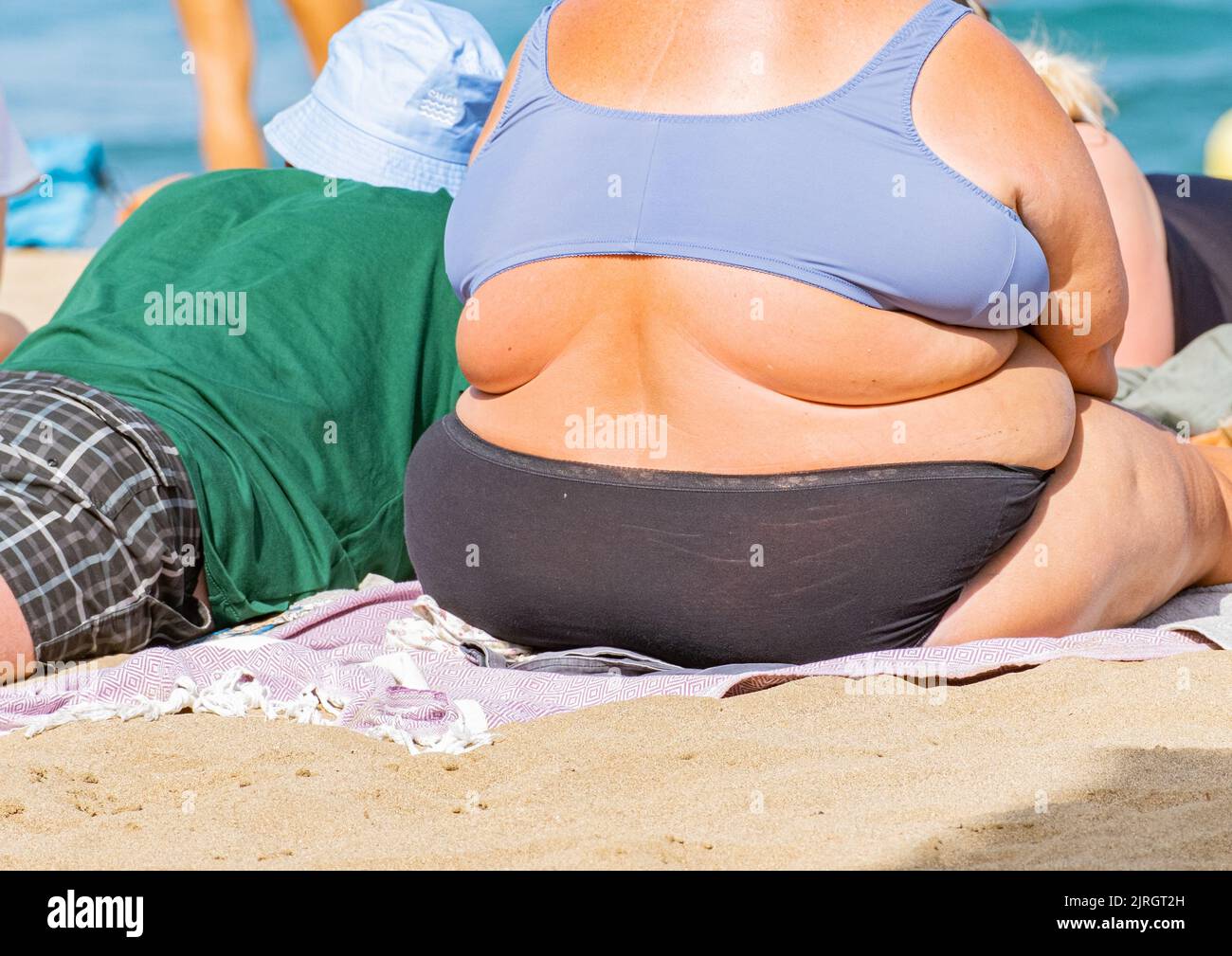 Donna obesa che prende il sole sulla spiaggia in Spagna Foto Stock