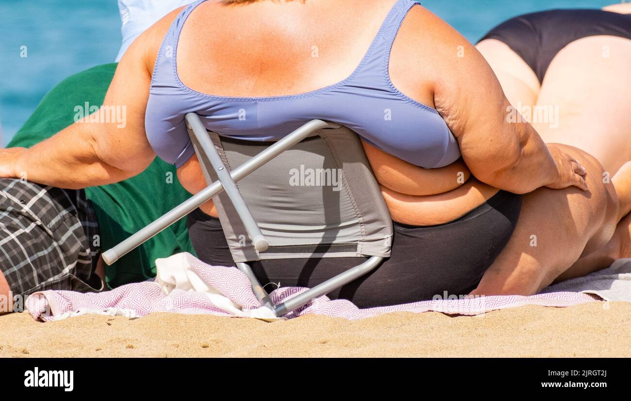 Donna obesa che prende il sole sulla spiaggia in Spagna Foto Stock