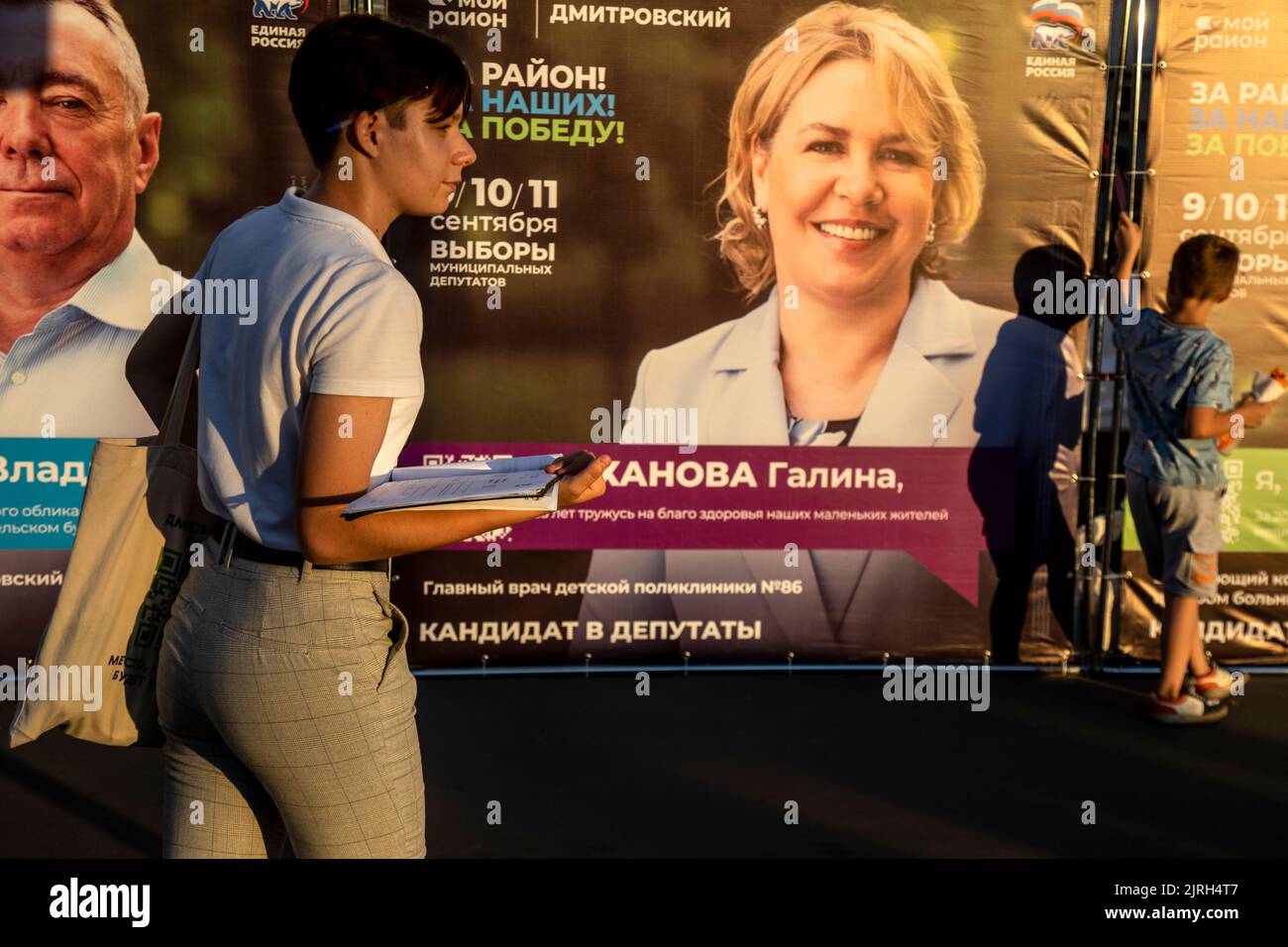 Mosca, Russia. 24th agosto 2022. Un volontario raccoglie le istruzioni degli elettori a striscioni pubblicitari di candidati di deputati del partito politico della Russia unita durante la campagna elettorale dei deputati dei comuni di Mosca, Russia Foto Stock