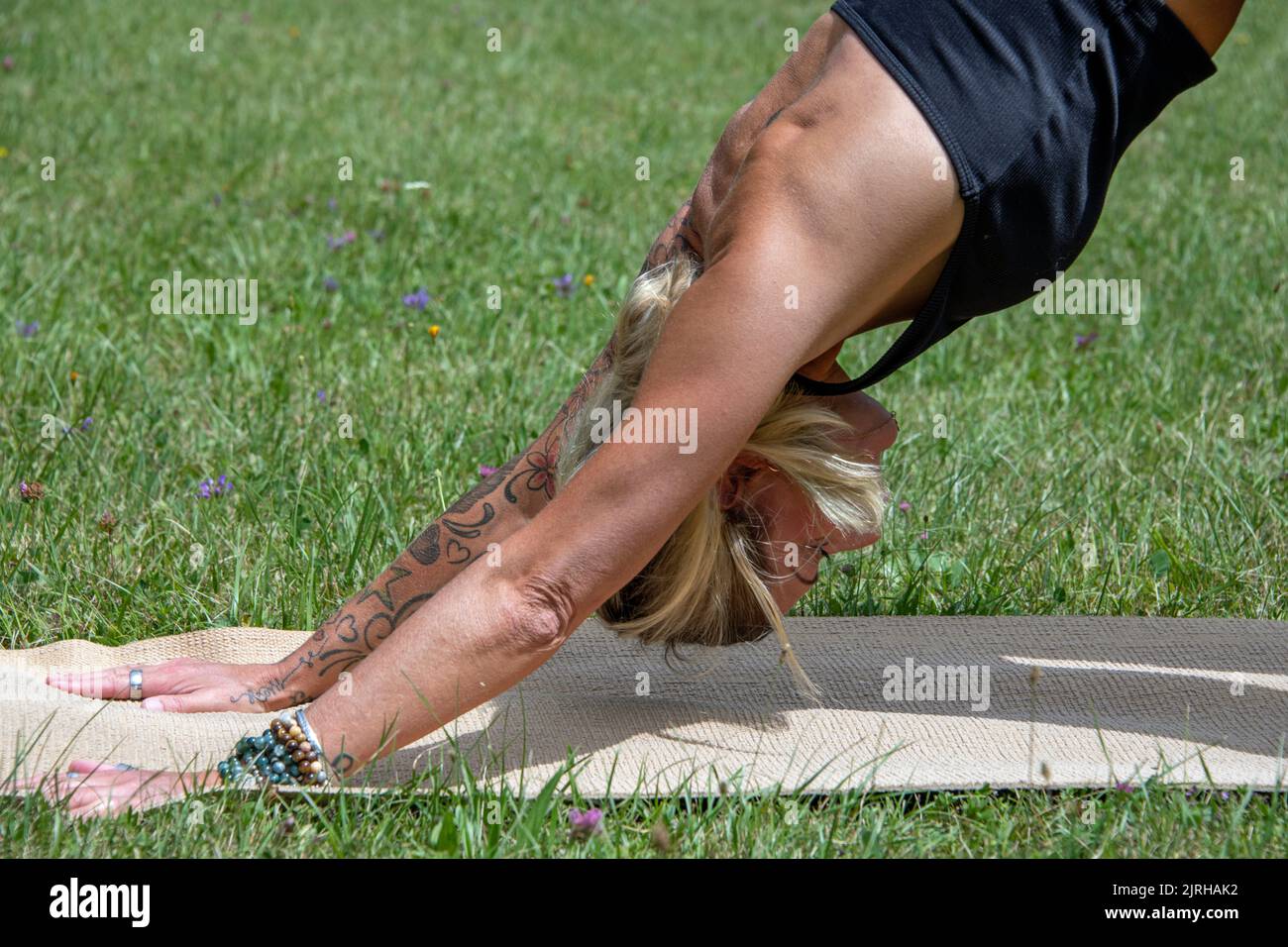 Parte del corpo di una donna europea con tatuaggi e piercing fare yoga Foto Stock
