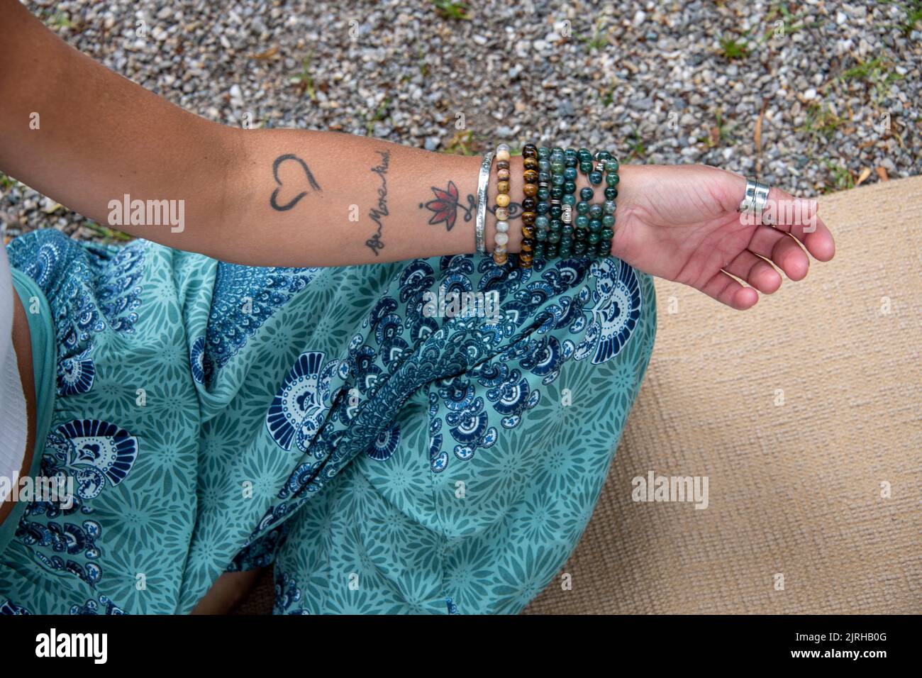 Braccio e mano di una donna europea con tatuaggi e gioielli Foto Stock