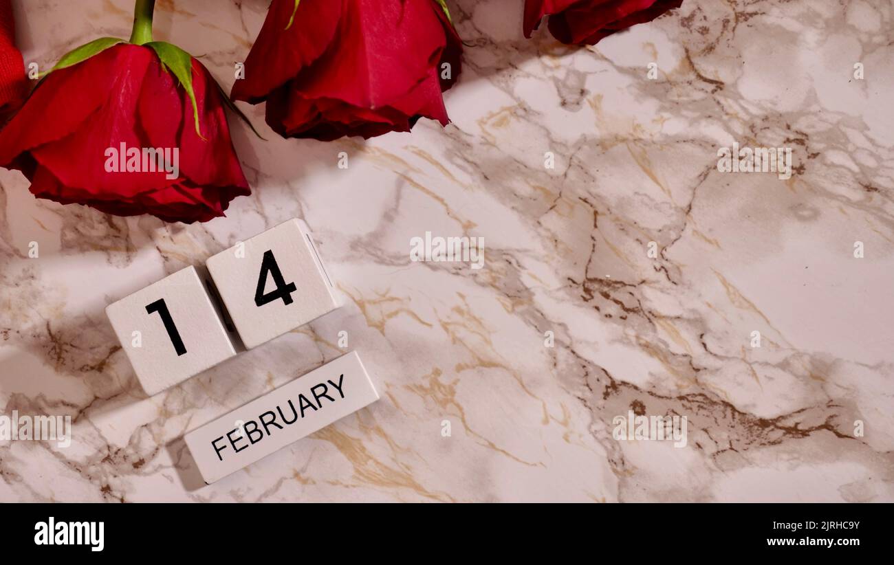 Festa Flatlay, composizione per San Valentino il 14 febbraio. Caffè in una tazza rossa e fiori rossi di rosa a casa a letto Foto Stock