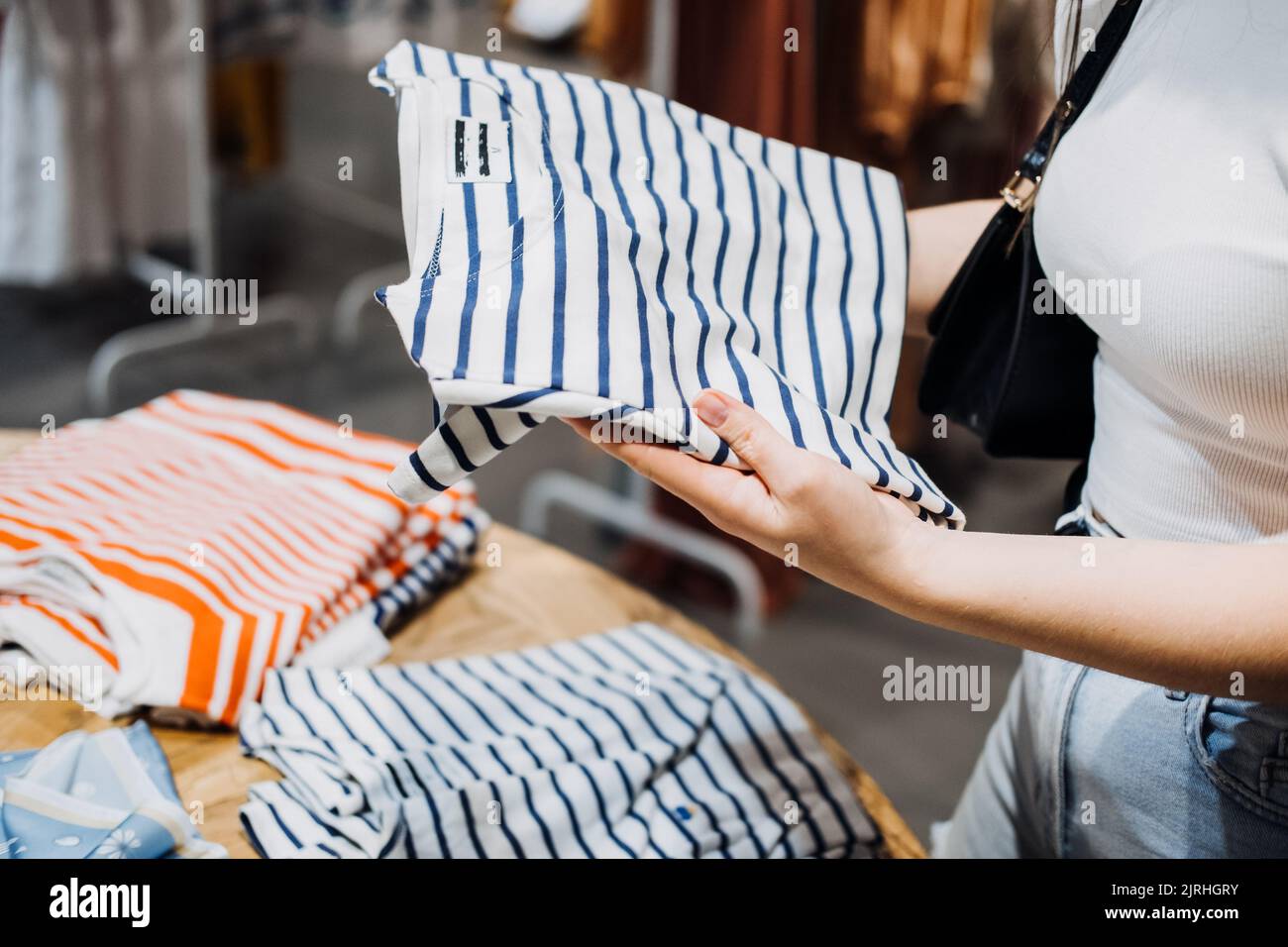 Moderna Latina giovane donna scegliendo 100% cotone biologico indossare t shirt in moderno eco-friendly negozio Foto Stock