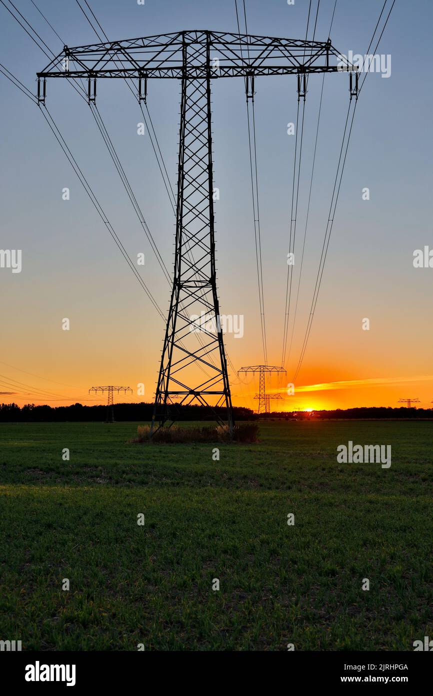 Freileitungstrasse im Sonnenuntergang Übertragung Energie Foto Stock