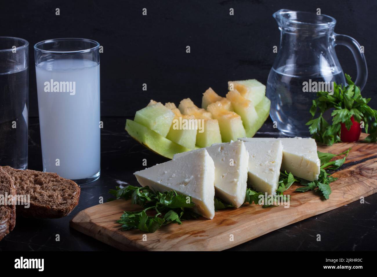 Raki turco con acqua sul tavolo con melone a fette e antipasto, tradizionale alcool turco noto come raki, chill con gli amici al ristorante, cena Foto Stock