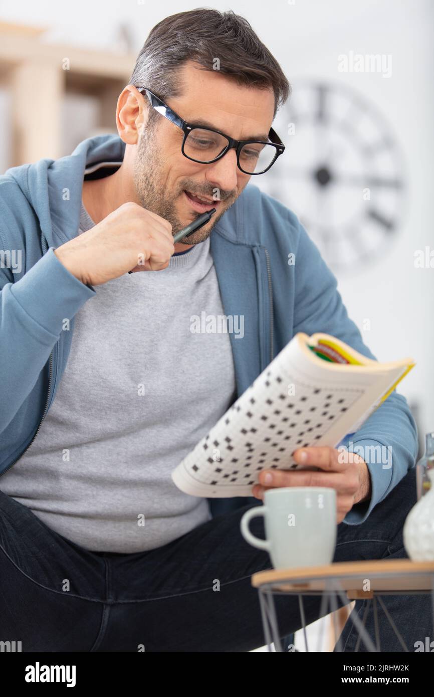 uomo seduto a fare un puzzle cruciverba a casa Foto Stock