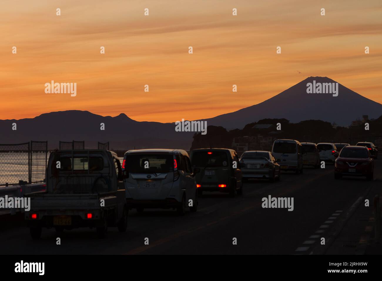 Auto su una strada con il Monte Fuji dietro al tramonto. Enoshima, Kanagawa, Giappone. Foto Stock
