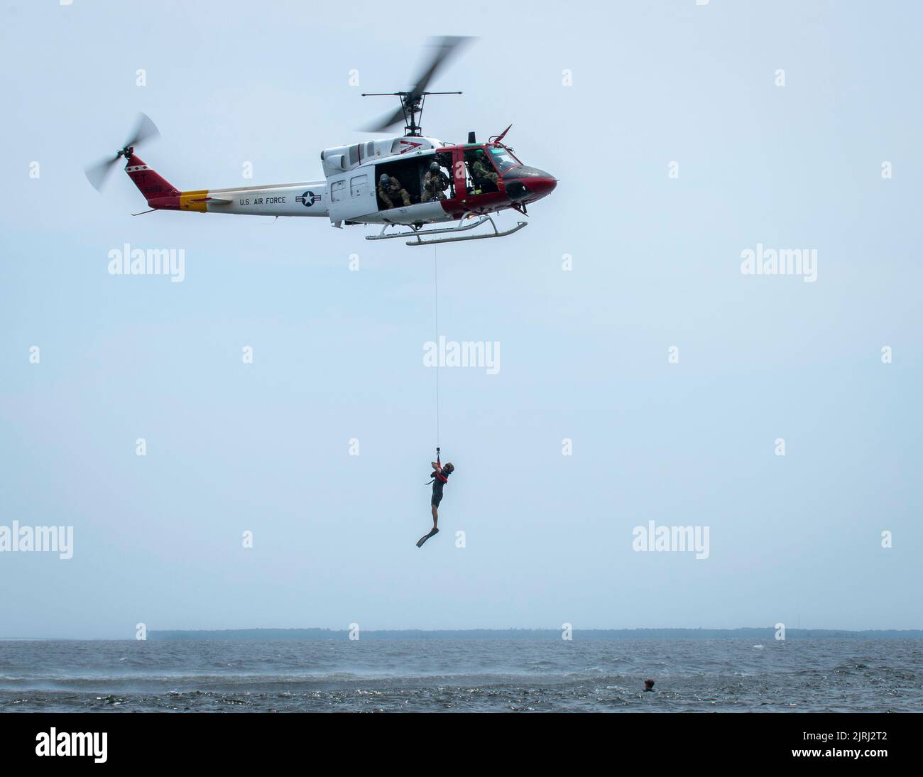 A 413th Flight Test Squadron UH-1 Huey solleva un istruttore di operazioni speciali dalle acque vicino alla base aeronautica di Eglin, Florida, per testare il sistema di argani dell'aeromobile il 16 agosto. Il 413th FLTS, l’unica unità di test per lo sviluppo di alari rotanti dell’Air Force, ha fornito un ulteriore realismo alla sopravvivenza, all’evasione, alla resistenza e all’addestramento alla fuga, consentendo agli Airmen di sperimentare la sensazione di un vero salvataggio in acqua. (STATI UNITI Foto dell'aeronautica/Samuel King Jr.) Foto Stock