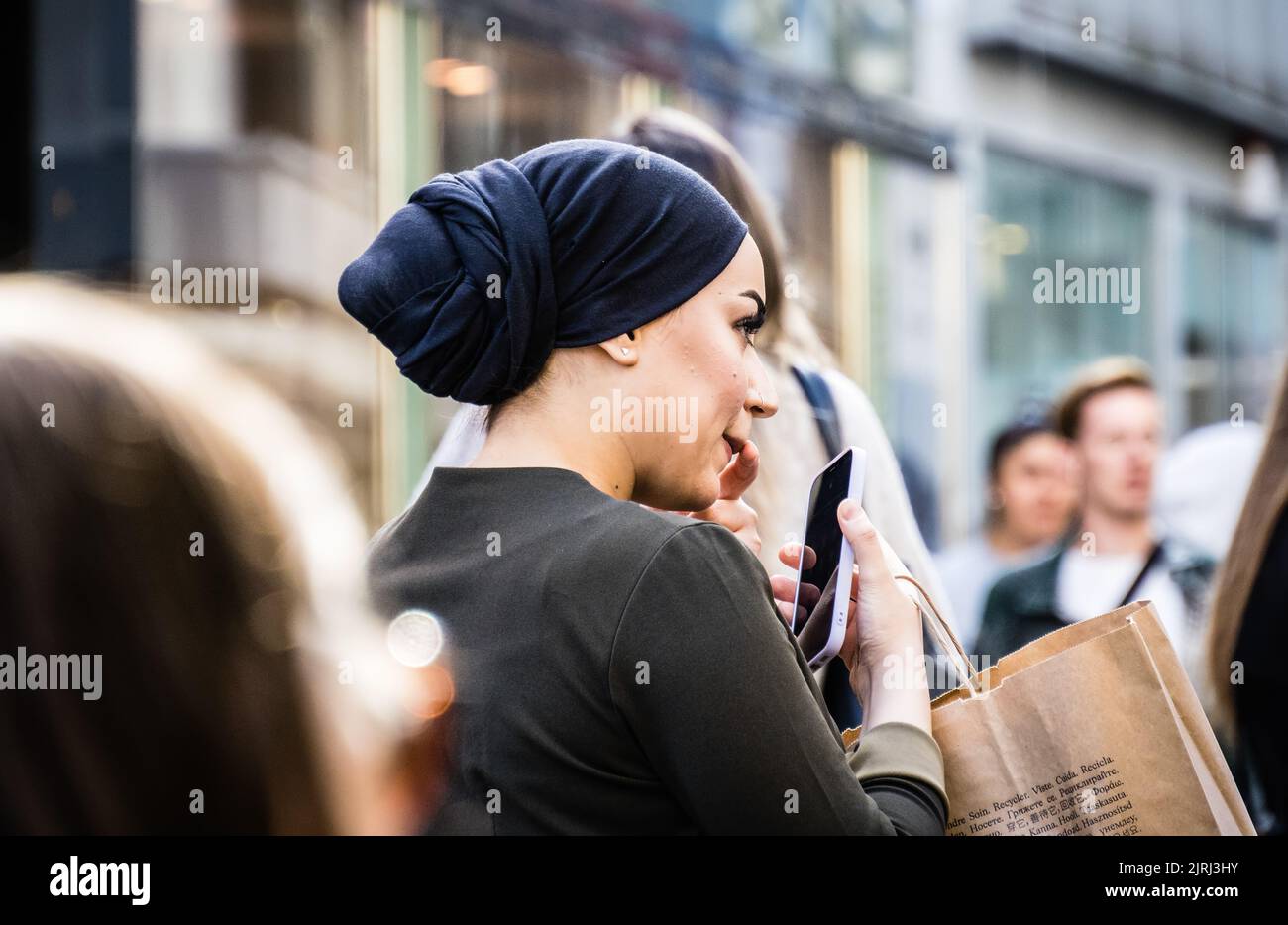 Una donna elegante consulta il suo telefono mentre fa shopping a Colonia Foto Stock