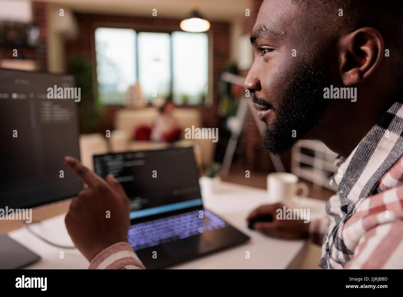 Ingegnere informatico afroamericano che programma l'interfaccia di codice binario, usando lo script css html e la crittografia sul computer. Server di sicurezza di codifica freelance maschio con applicazione di sviluppo software. Foto Stock