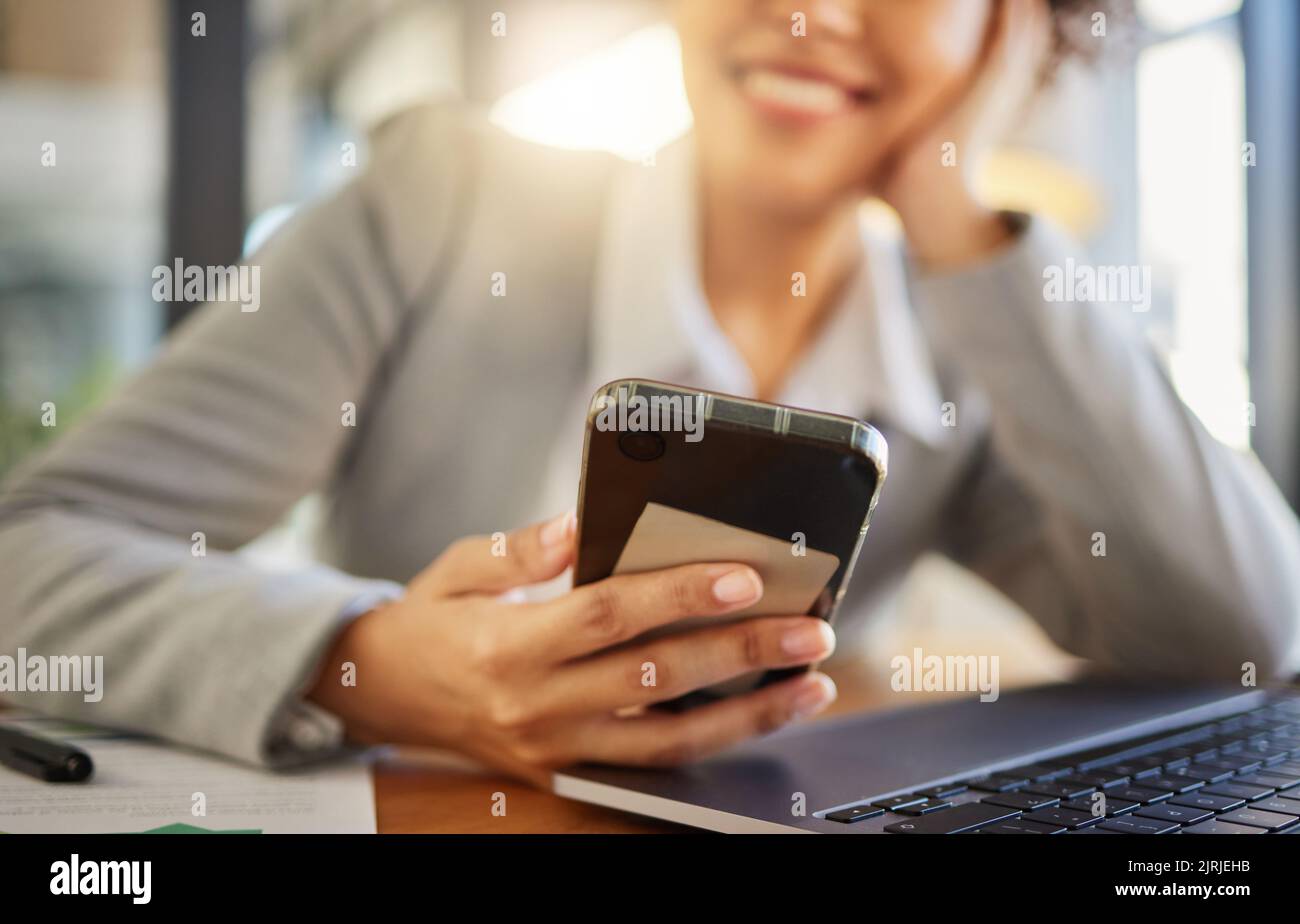 I dipendenti che utilizzano un telefono mentre lavorano su un computer portatile, sorridono e si rilassano in un ufficio moderno. Primo piano di una donna che legge i social media, messaggio di testo Foto Stock