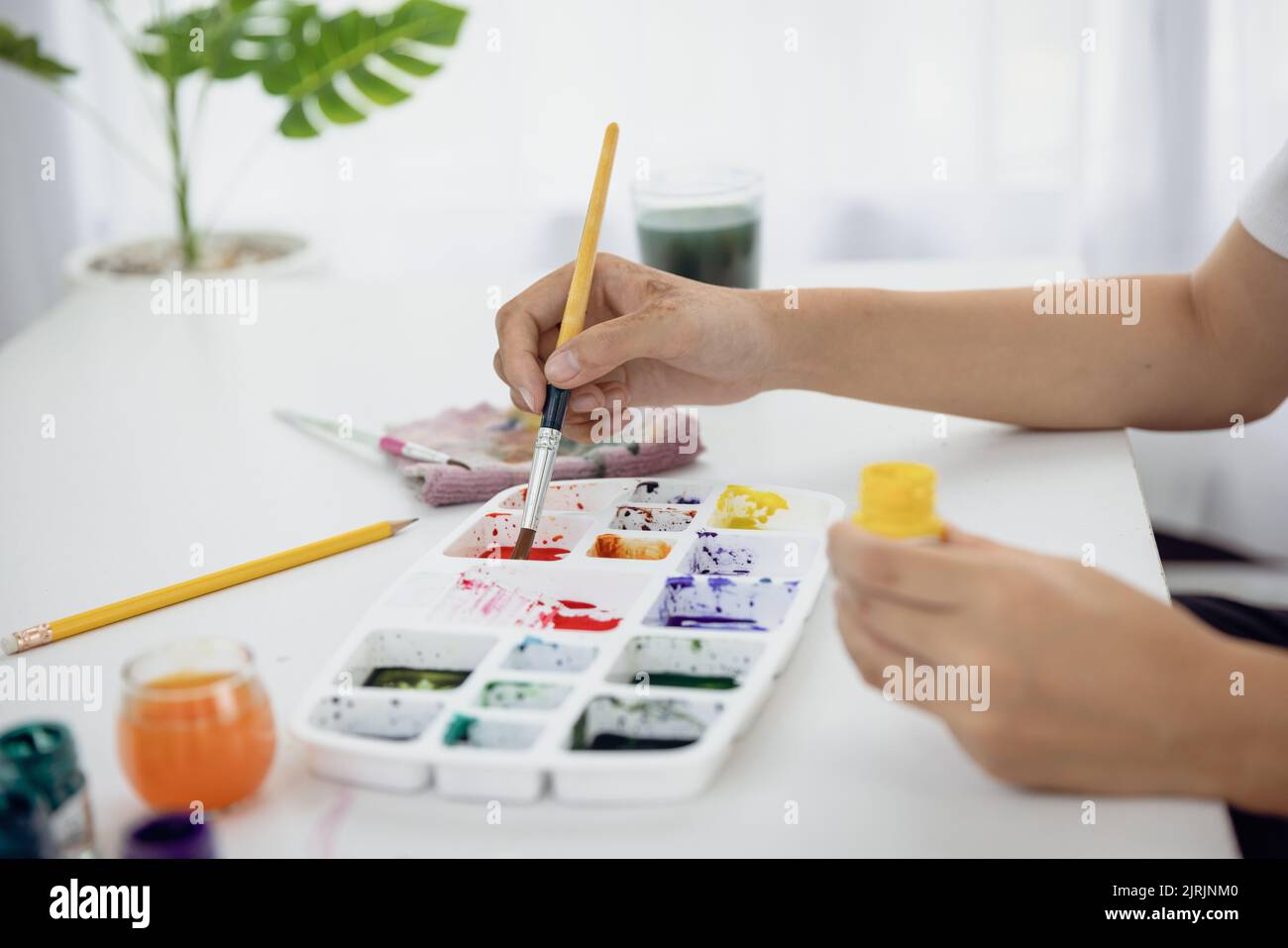 Primo piano Paint su una tavola da disegno in casa per creare arte con acquerelli e pennelli. Foto Stock