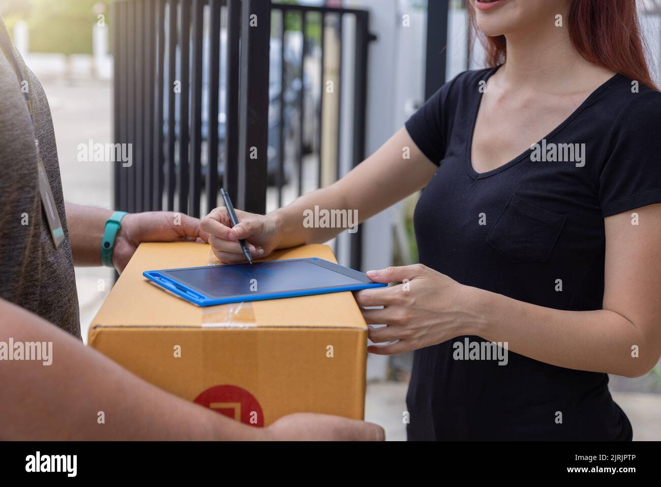 La mano femmina accetta la consegna delle scatole dal corriere, consegna in linea. Foto Stock