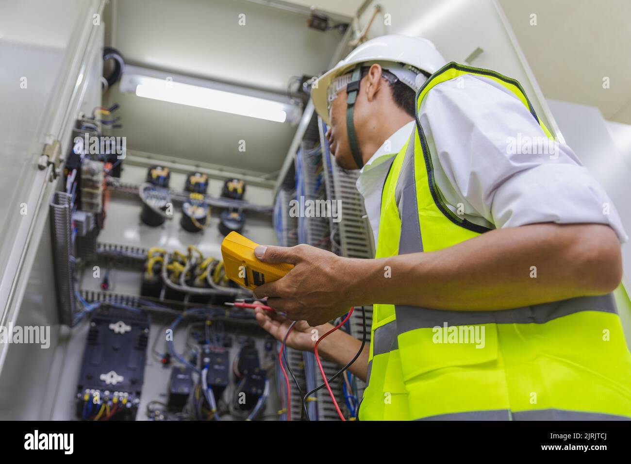 Elettricista che installa i fili dei cavi elettrici e la scatola di commutazione dei fusibili. Multimetro nelle mani di elettricisti dettaglio.elettricista riparazione controllo elettrico c Foto Stock