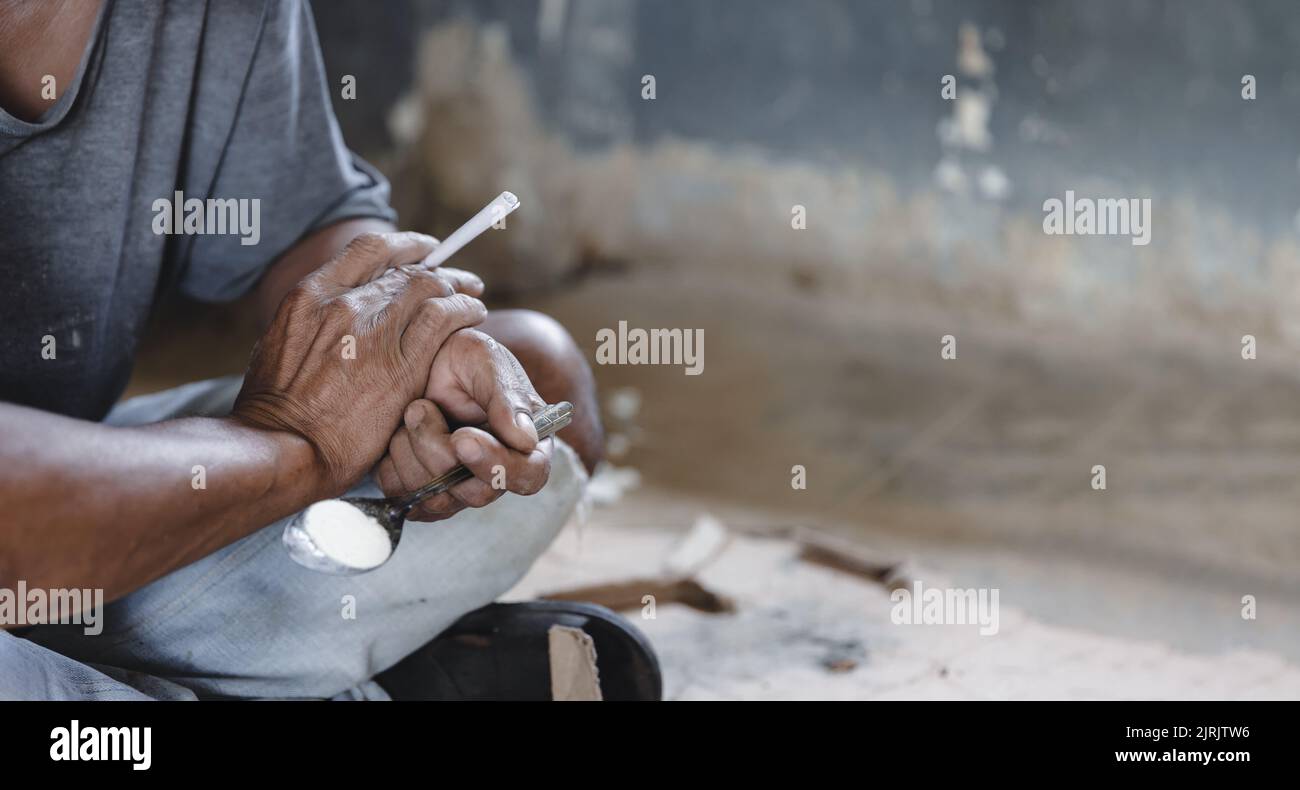 Tossicodipendenti nella stanza buia. Tossicodipendente/junkie preparazione di farmaci con un cucchiaio e un accendino. Polvere bianca e una siringa. Concetto di farmaco. Droga internazionale ab Foto Stock