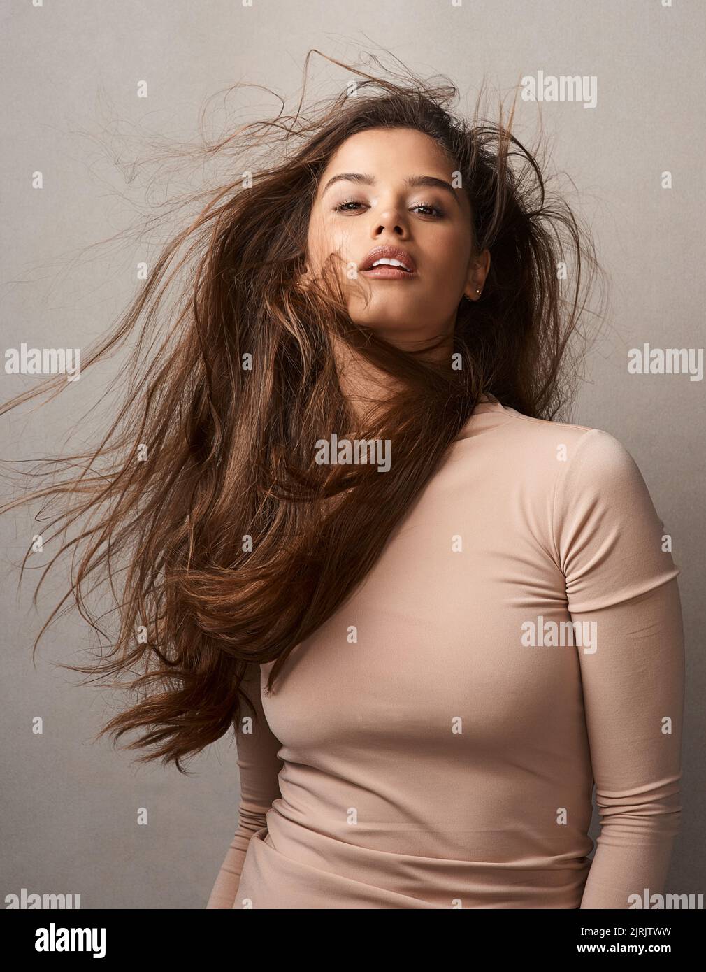 Lascia che i tuoi capelli esprimano il tuo umore. Ritratto di una bella giovane donna in posa con il vento nei suoi capelli in studio. Foto Stock