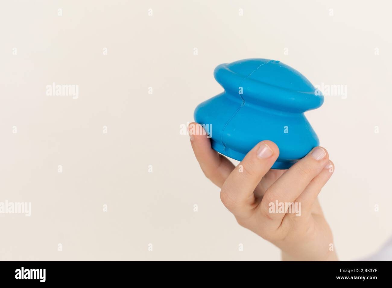 Primo piano delle ventose in silicone blu per massaggiare tenute da una donna medico su sfondo beige. Terapia di cupping. Foto Stock