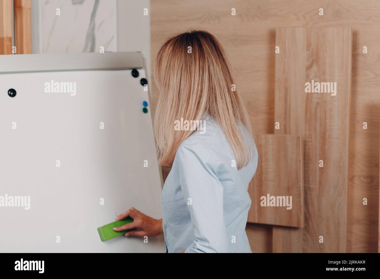 Donna d'affari giovane allenatore adulto in ufficio cancellare con modello vuoto lavagna a fogli mobili lavagna bianca Foto Stock