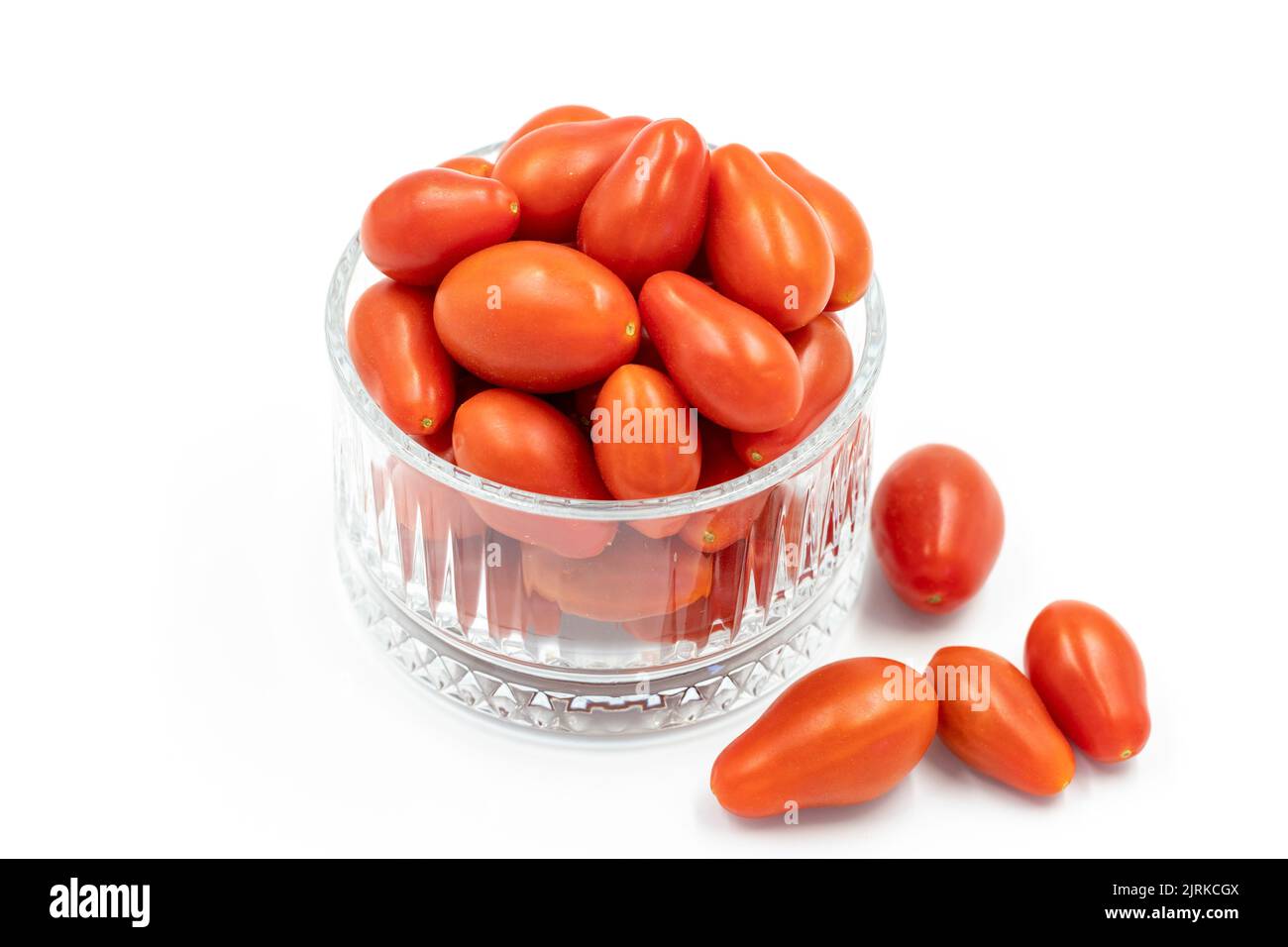 Pomodoro di ciliegia. Pomodori piccoli in ciotola di vetro isolato su fondo bianco. Verdure, cibo vegano sano. Primo piano Foto Stock